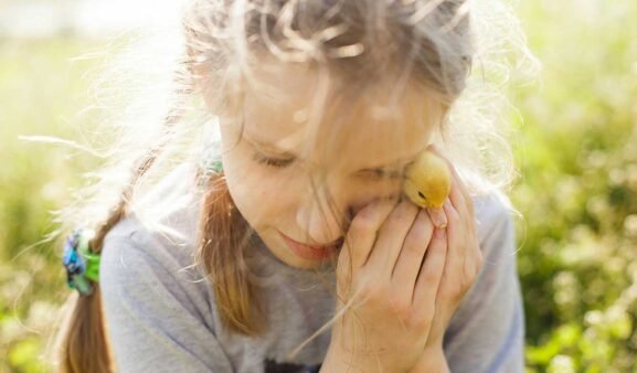 Mädchen in der Natur mit einem Kücken.